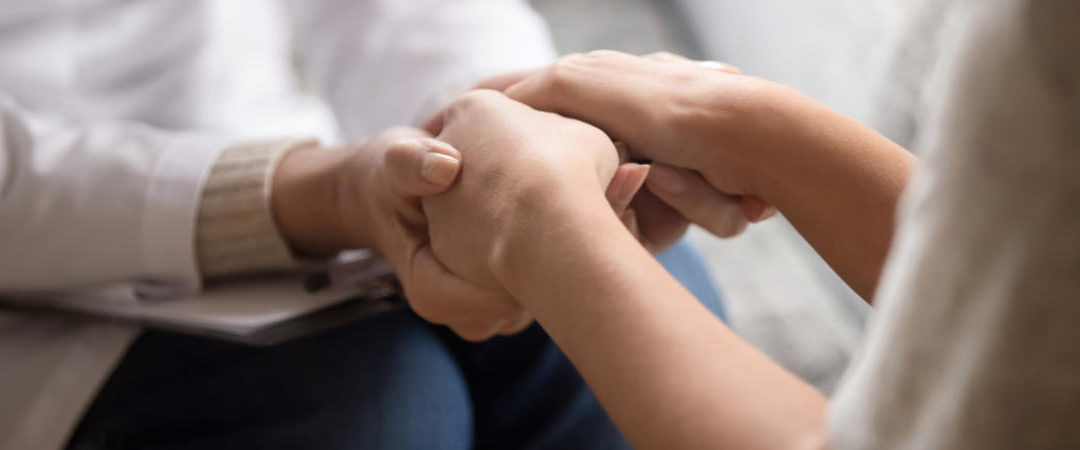 Close up image doctor in white uniform holding hands of female patient, showing support